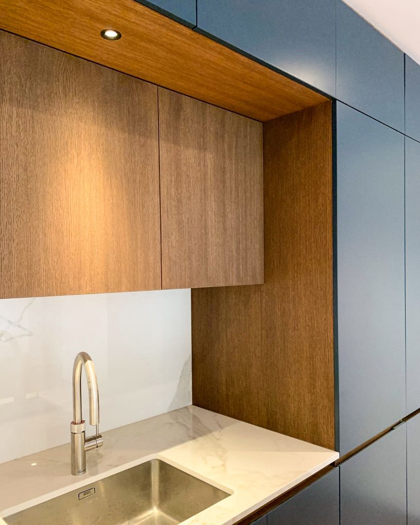 recessed walnut cabinets above sink wiith spot light