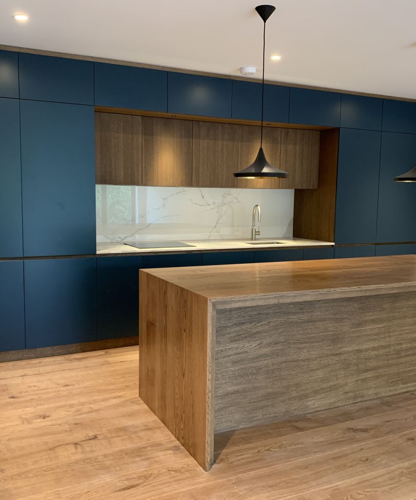 galley kitchen in dark blue with walnut recessed cupboards and white marble worktop